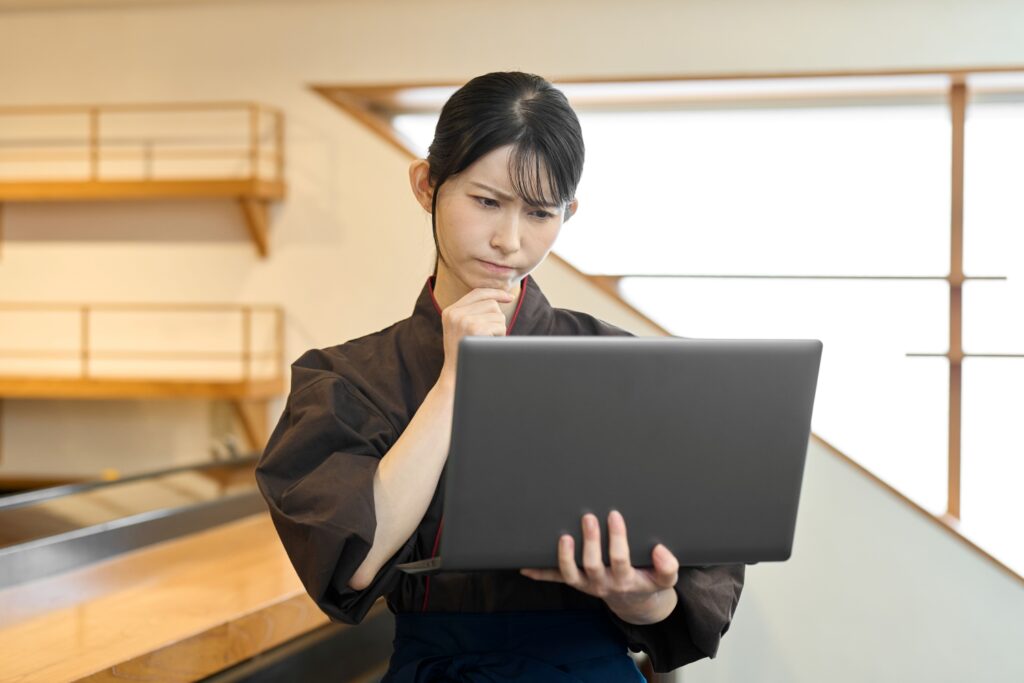 パソコンを持って悩む飲食店の従業員